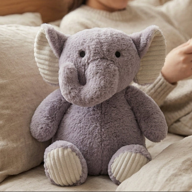 Person reading a book with a purple elephant plush toy on a couch