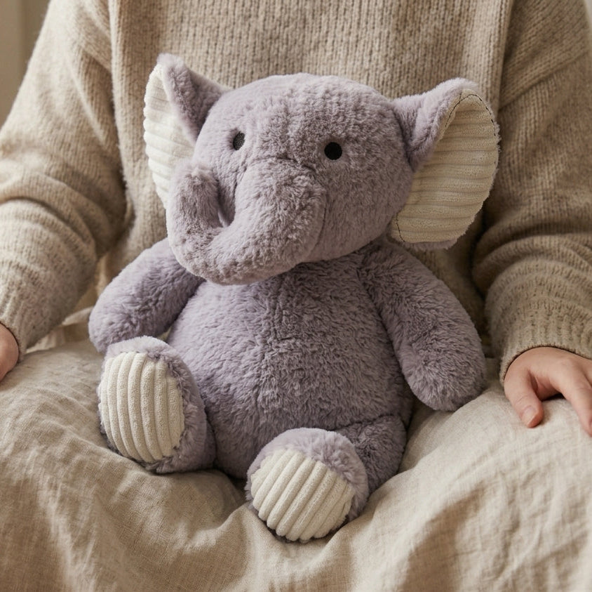 Person holding a plush elephant toy on a beige couch